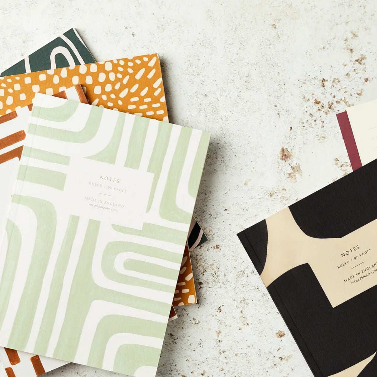 Abstract pale green A5 ruled notebook displayed with other patterned notebooks from Ink & Bloom Paper Co