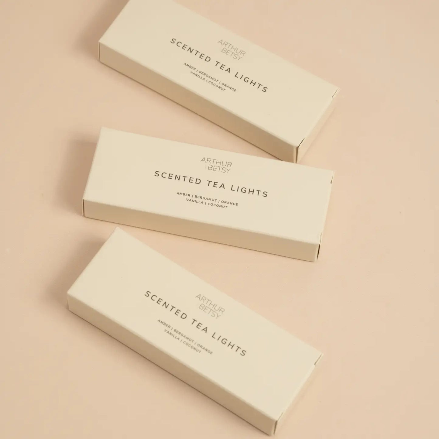 Three Arthur Betsy tea light boxes arranged in a neat flat lay on a blush-toned surface, ideal for gifting or display