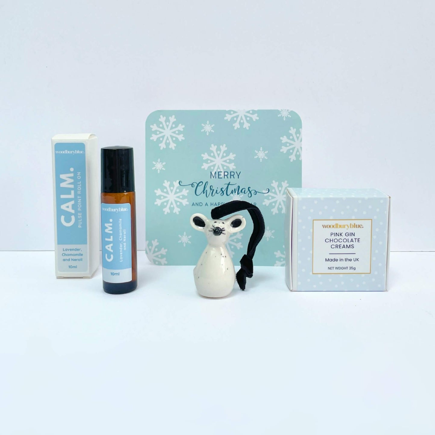 Calm aromatherapy roll-on, ceramic mouse ornament and pink gin chocolates in front of matching Christmas card from Silent Night gift box.