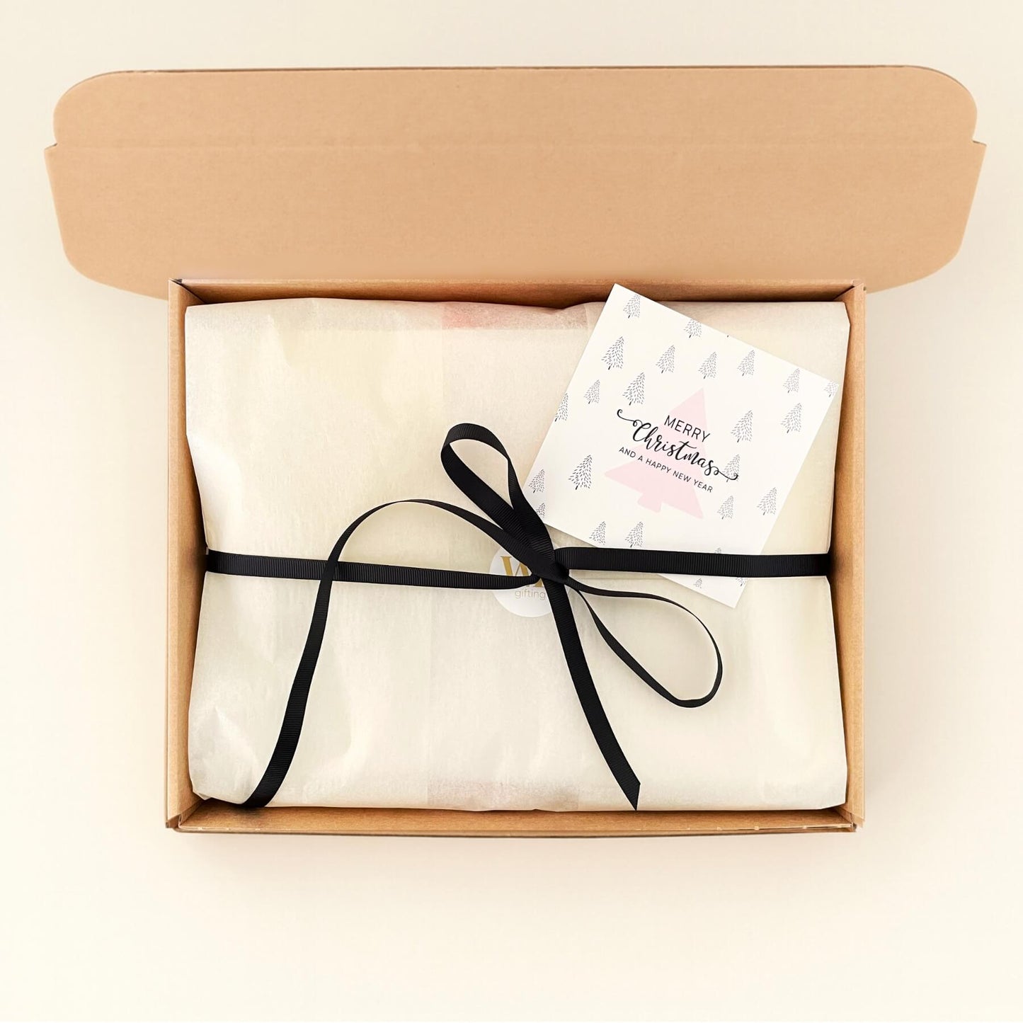 Cosy Christmas Gift Box wrapped in tissue with a black ribbon and Christmas card ready to send.