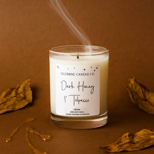 Dark Honey and Tobacco soy wax candle by Illumine Candle Co with honey drizzle and tobacco leaves on a brown background