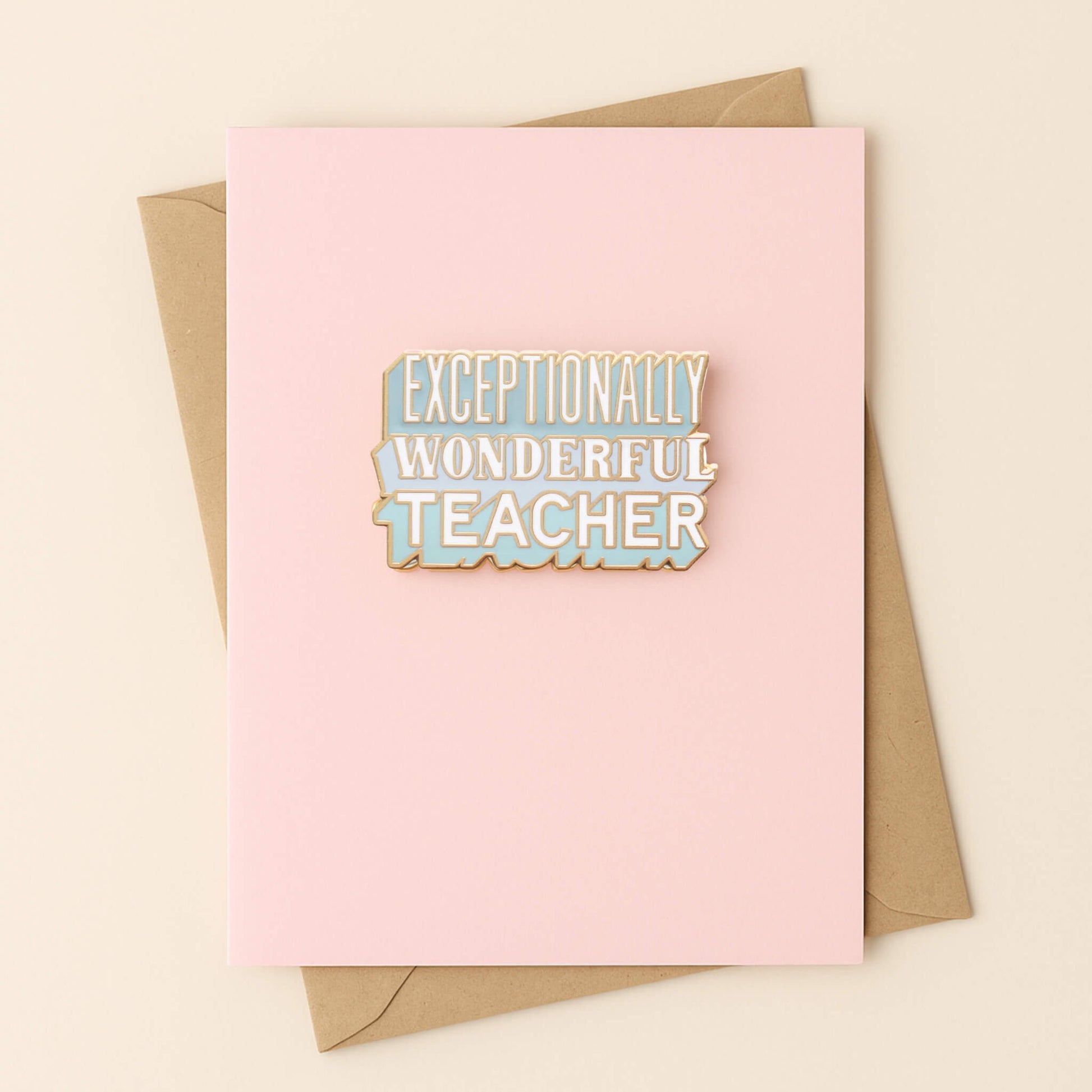 Exceptionally Wonderful Teacher enamel pin badge displayed on a pastel pink greetings card with kraft envelope.