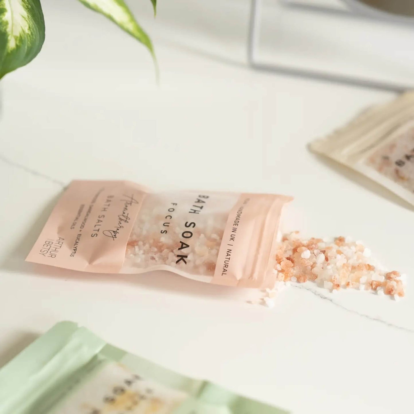 Bath salts spilling from Arthur Betsy sachet on white surface
