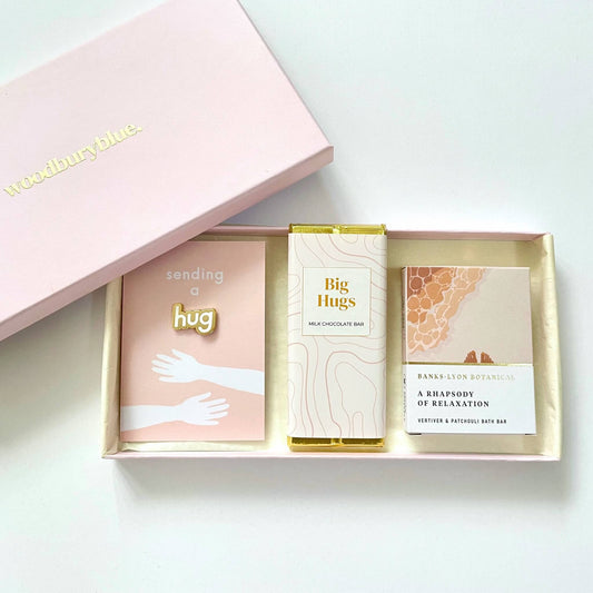 A Hug in a Letterbox gift set with chocolate, enamel hug pin badge and bath oil.