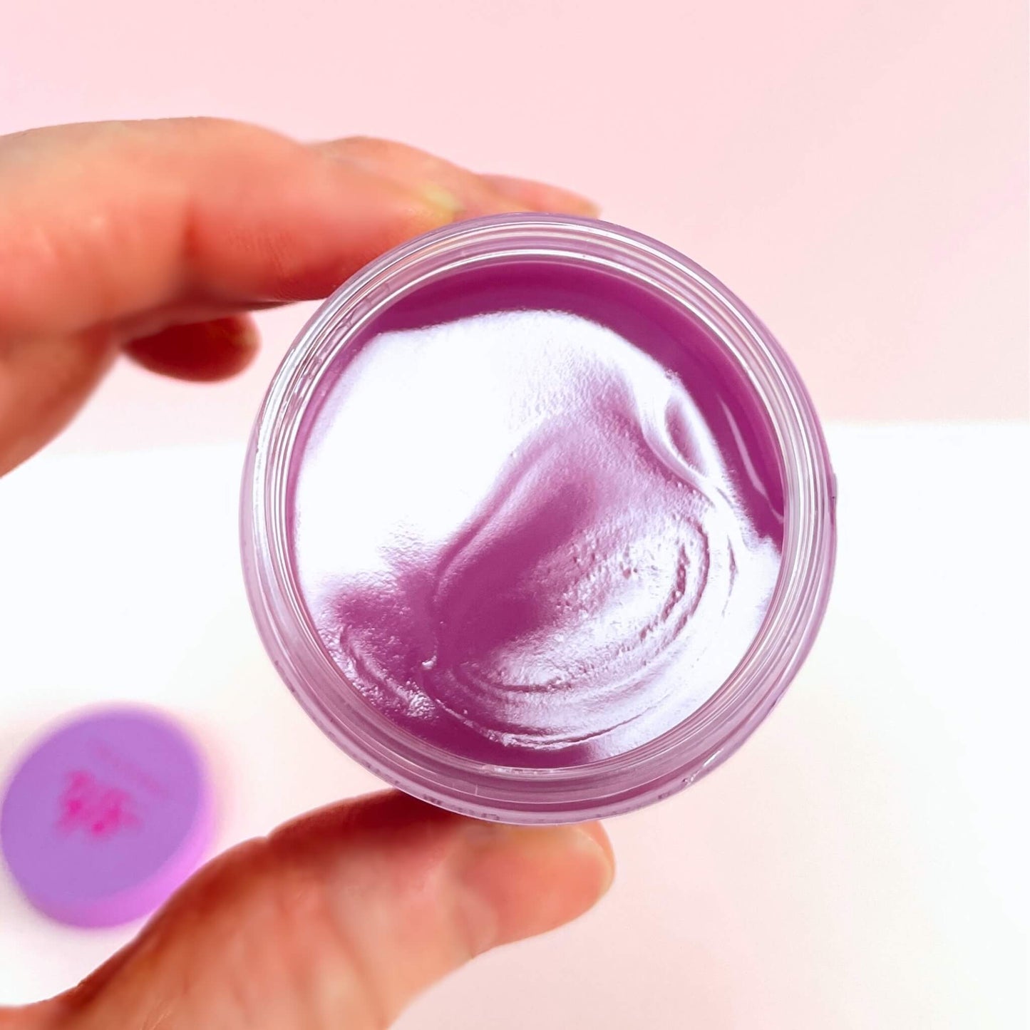 hand holding an opened pot of vanilla lip mask