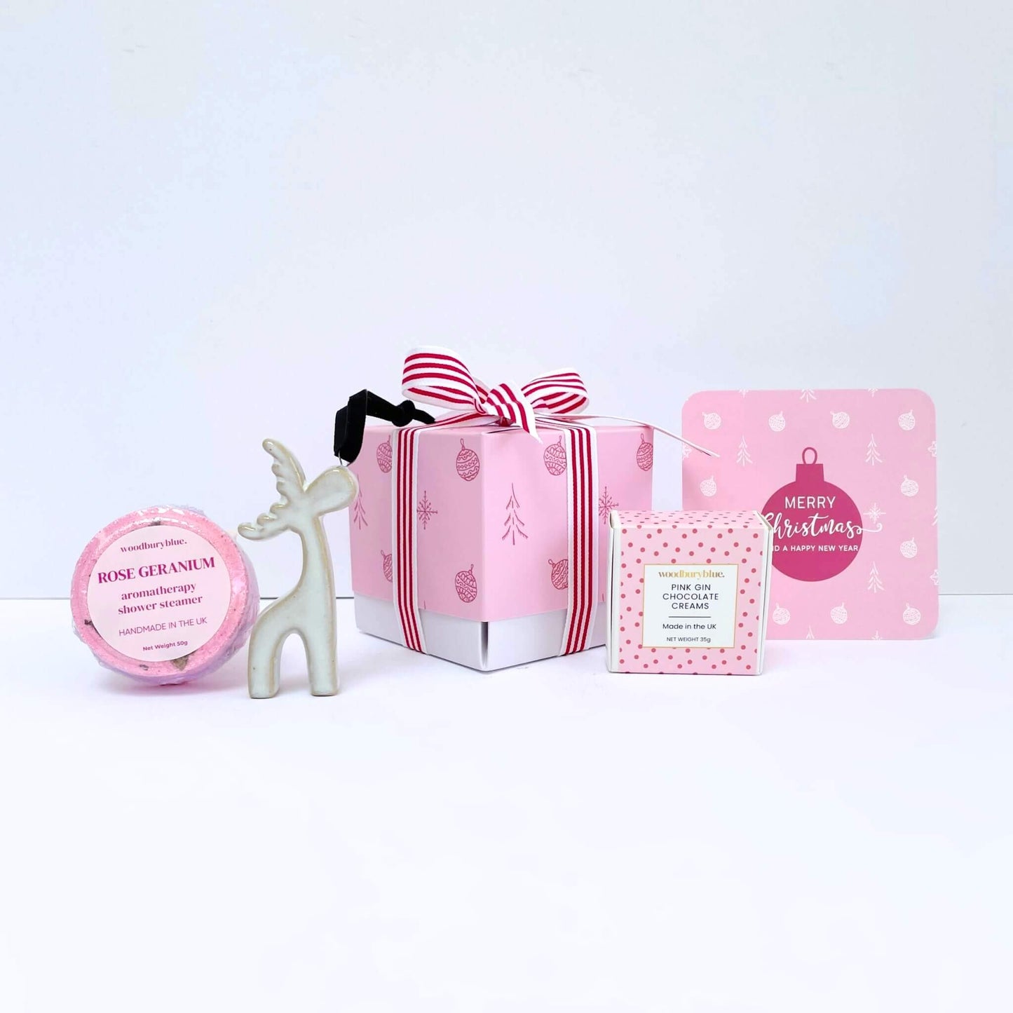 Collection of pink and white Christmas-themed products with a gift box and notecard on a white background