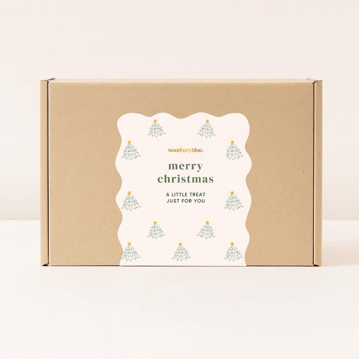 Kraft gift box with scalloped white Merry Christmas sticker decorated with small Christmas trees from Woodbury Blue