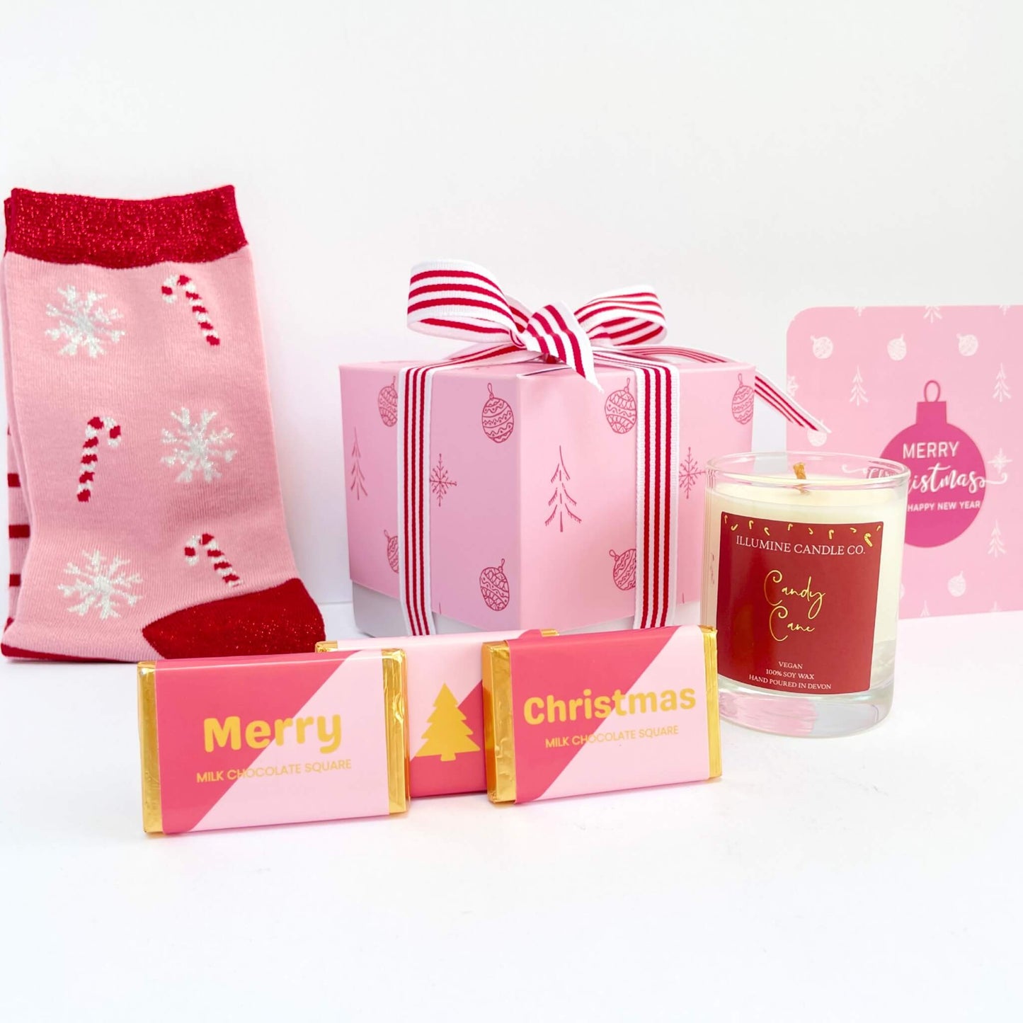 Pink ornament-print gift box with socks, candle and chocolates displayed with matching Christmas notecard
