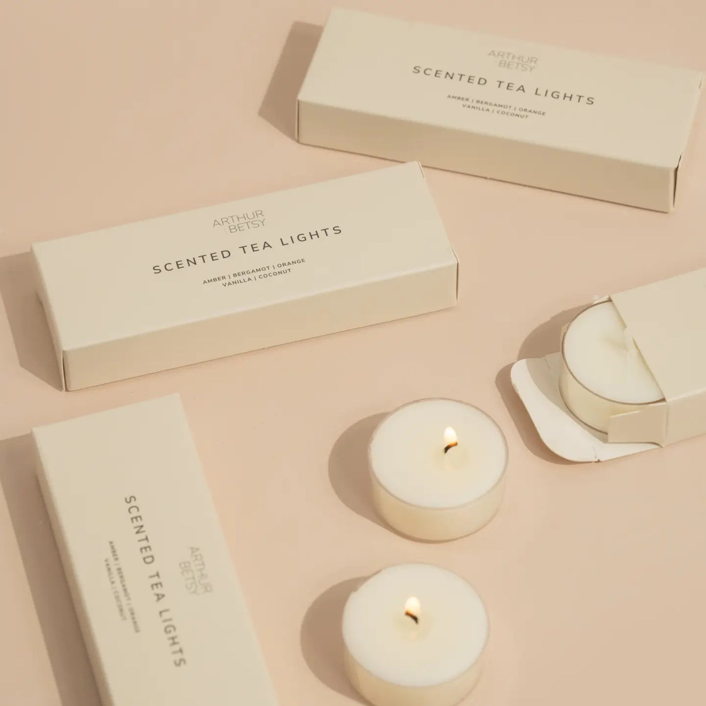 Arthur Betsy scented tea lights with open box and two candles lit, styled on a soft neutral background