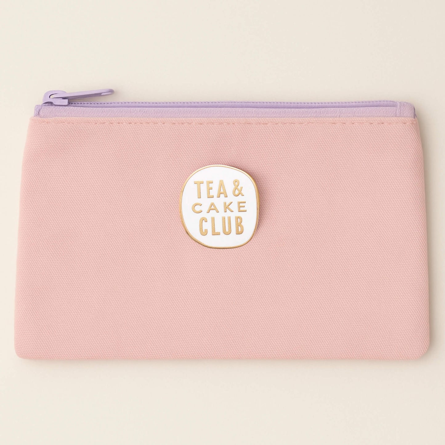 Tea and Cake Club enamel pin badge attached to a pastel pink pencil case with lilac zip.