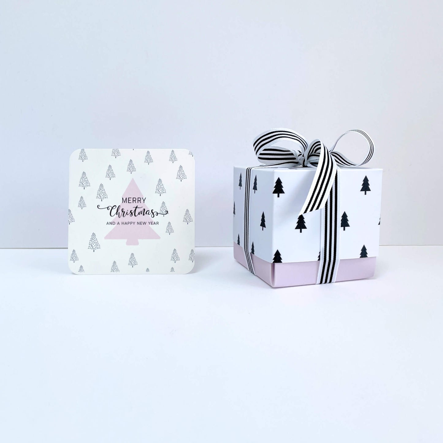 Merry Christmas notecard and white gift box with black tree design and striped ribbon