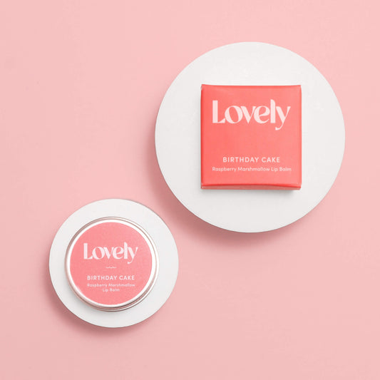 Lovely Skincare Birthday Cake Raspberry Marshmallow Lip Balm tin and box on circular white stands against pink background