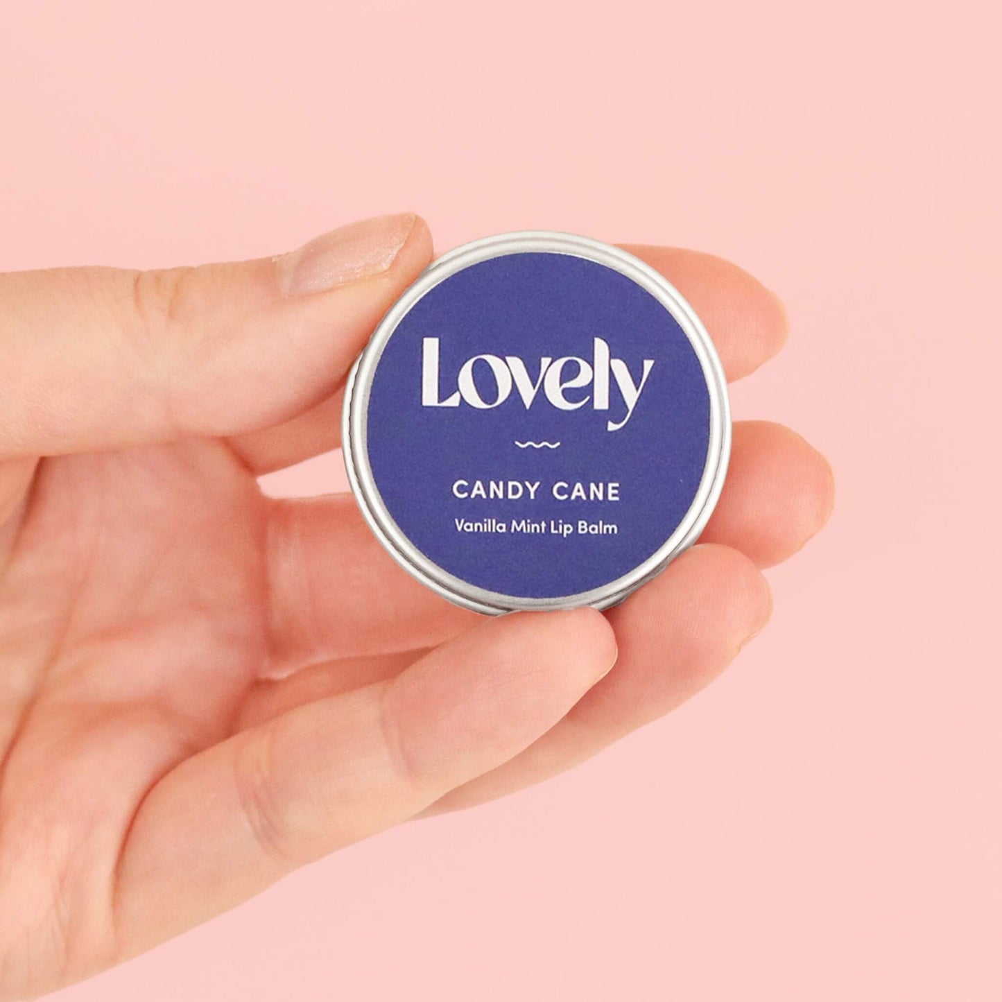 Hand holding Lovely Skincare Candy Cane Vanilla Mint Lip Balm tin