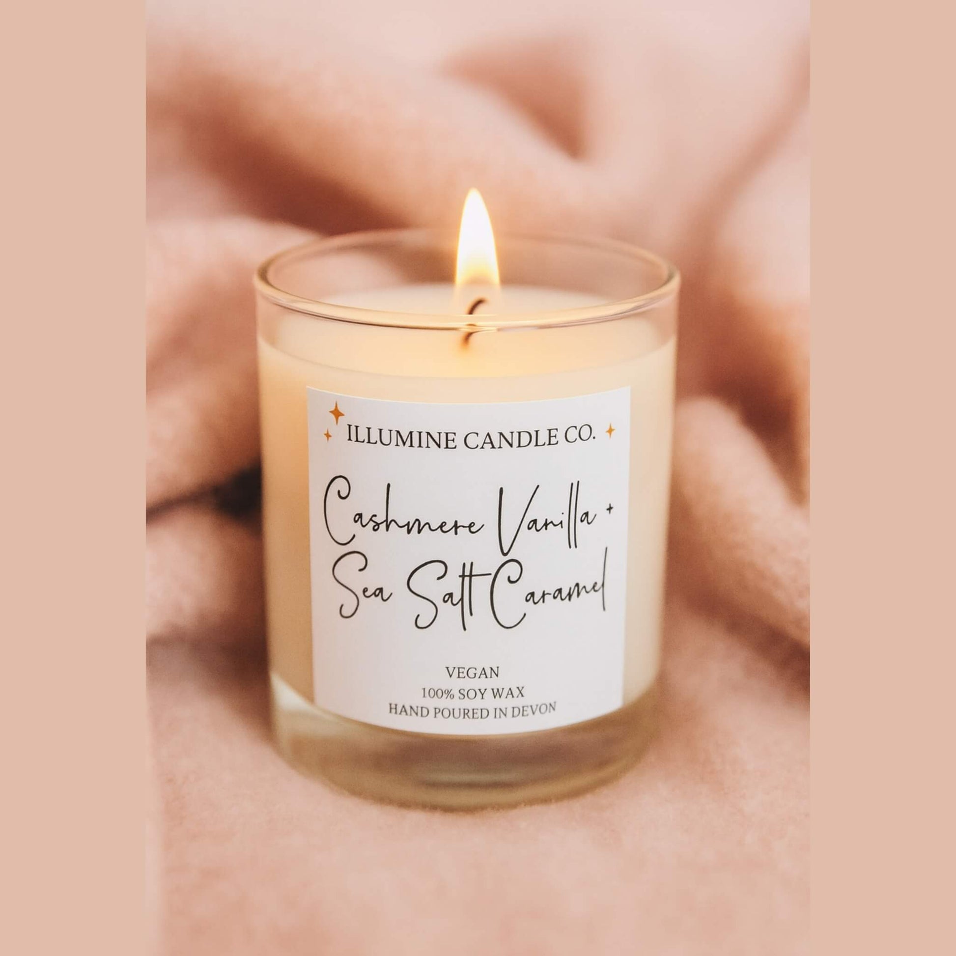 Cashmere Vanilla and Sea Salt Caramel soy wax candle by Illumine Candle Co, hand-poured in Devon, placed on a soft blush pink cashmere blanket