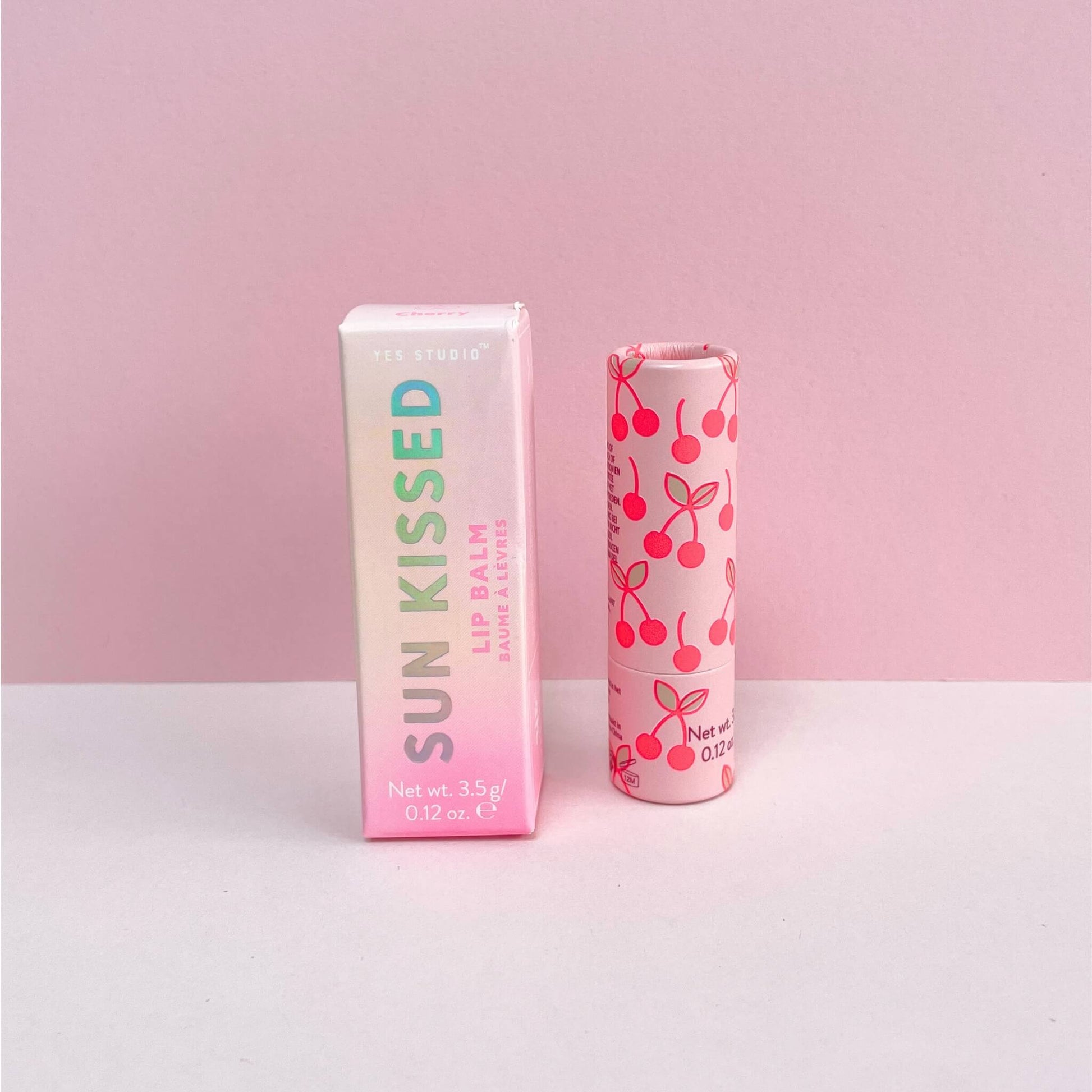 Sun-kissed cherry lip balm with it's packaging box on a pink background