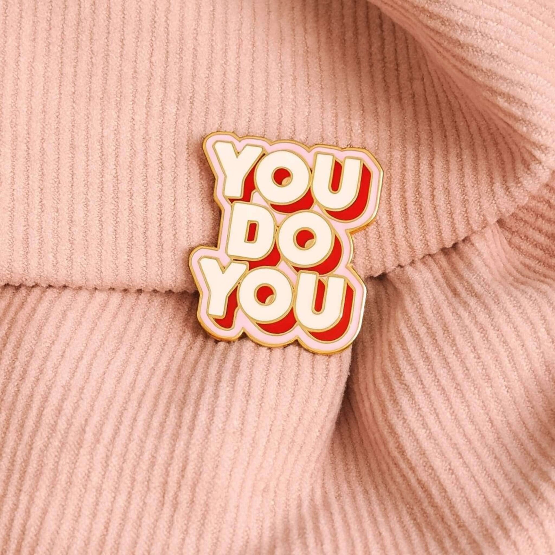 You Do You enamel pin badge with gold edge attached to a blush pink corduroy slouch bag