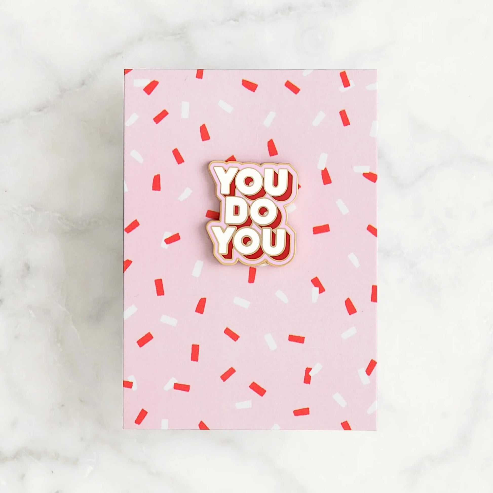 You Do You enamel pin badge with gold edge on pink card with red and white sprinkles