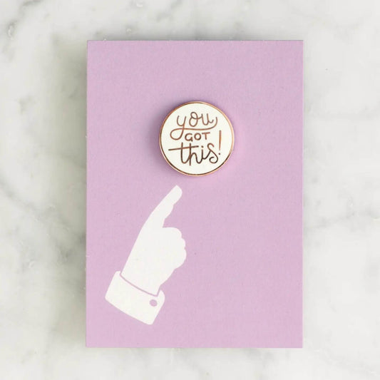 You Got This enamel pin badge on purple backing card on a marble surface.
