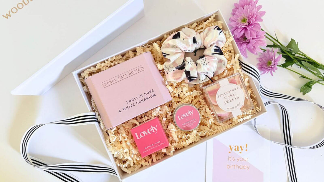 Open birthday gift box with sweets, lip balm, scrunchie and birthday card