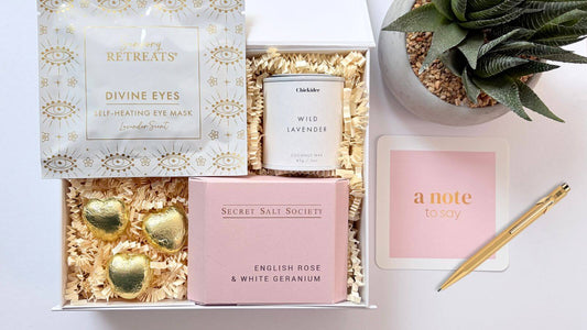 Curated gift box with lavender self heating eye mask, wild lavender candle, English rose bath infusion, chocolate hearts and handwritten note card.