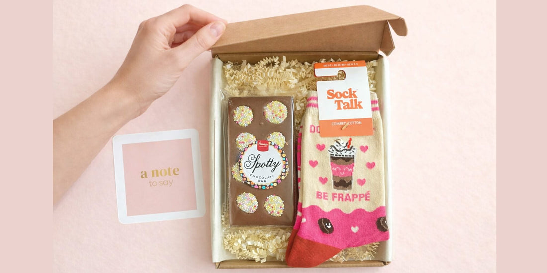 Open socks and chocolates letterbox gift box with patterned socks, chocolate bar and handwritten note
