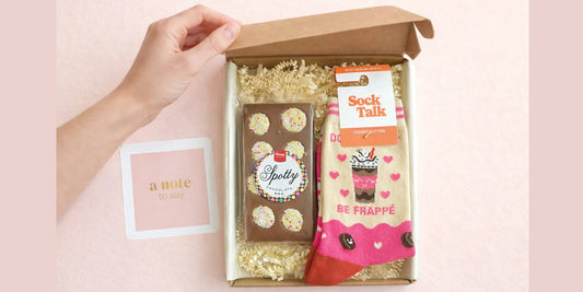 Open socks and chocolates letterbox gift box with patterned socks, chocolate bar and handwritten note
