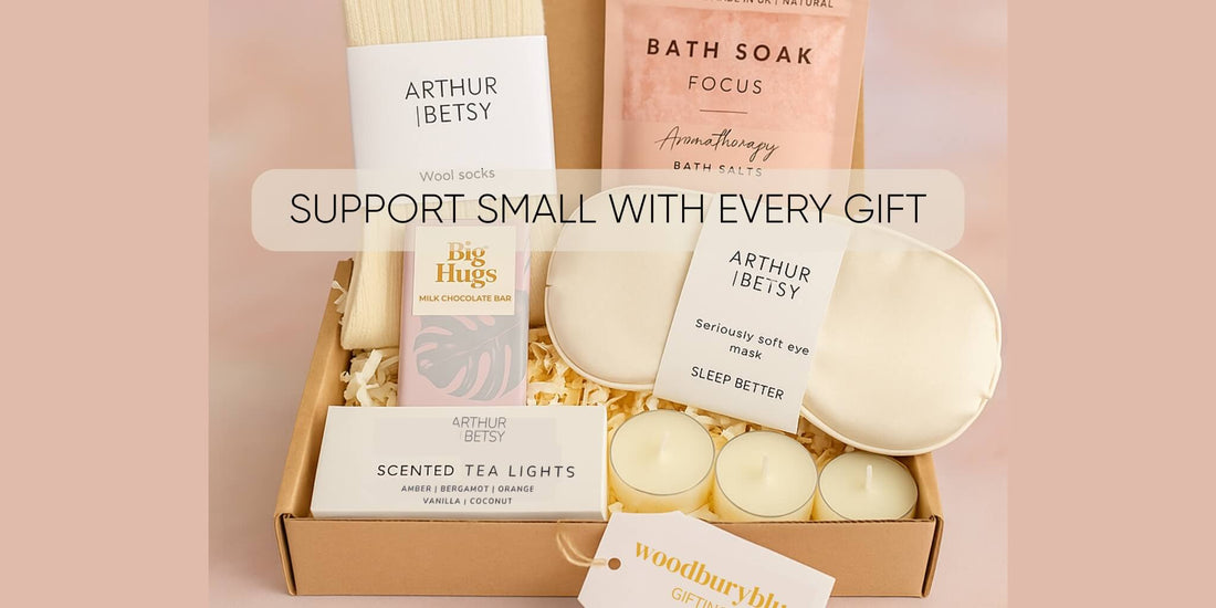 Beautifully presented gift box from Woodbury Blue featuring UK-made self-care products like socks, bath salts, chocolate, and tea lights, with overlay text that reads “Support Small With Every Gift.”
