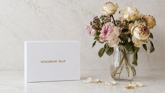 Woodbury Blue gift box beside slightly wilting flowers, showing a thoughtful gift alternative to sending flowers.