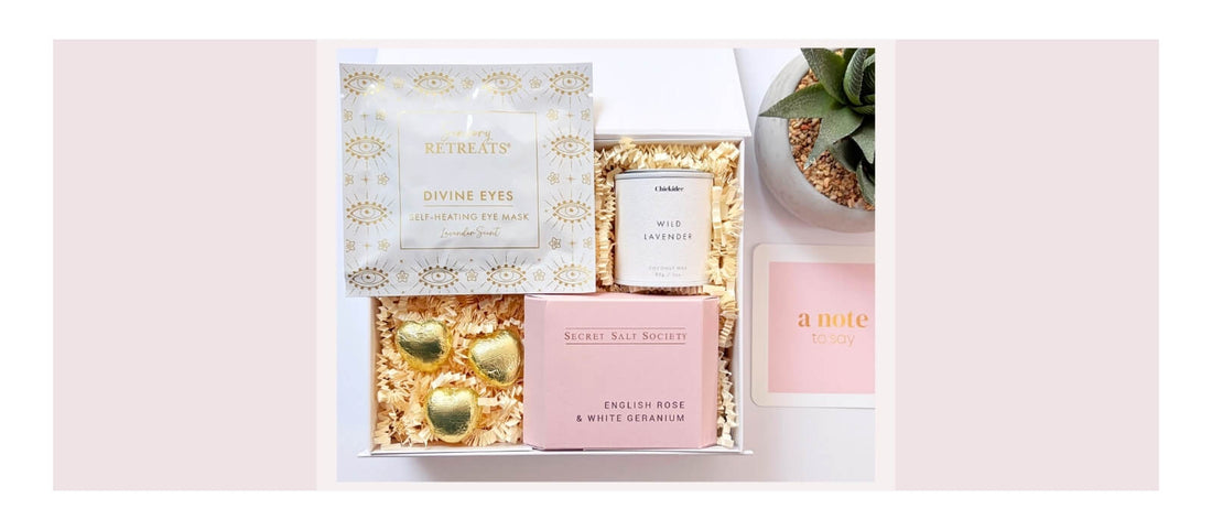 Pamper gift box with self care treats, chocolate hearts, lavender candle, eye mask and handwritten note card.