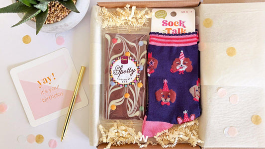 Birthday gift box with patterned socks, chocolate bar and birthday card