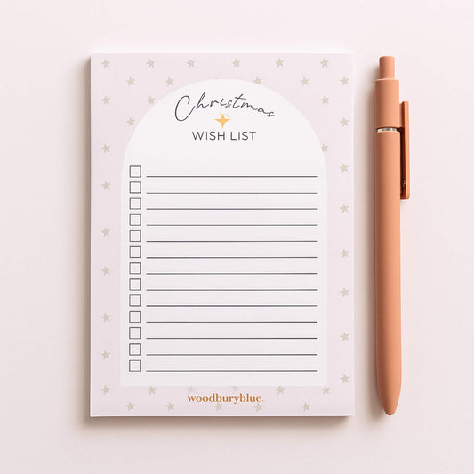 A6 Christmas Wish List Notepad by Woodbury Blue with soft grey stars and a blush background, styled with a peach pen.