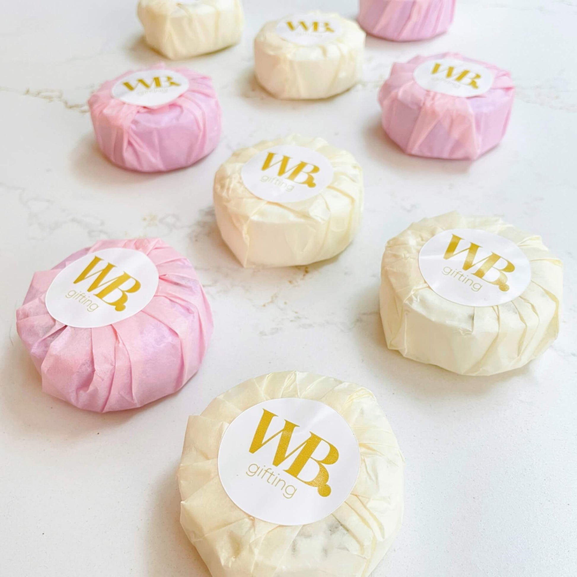 Collection of pastel-wrapped Woodbury Blue shower steamers arranged on a white surface