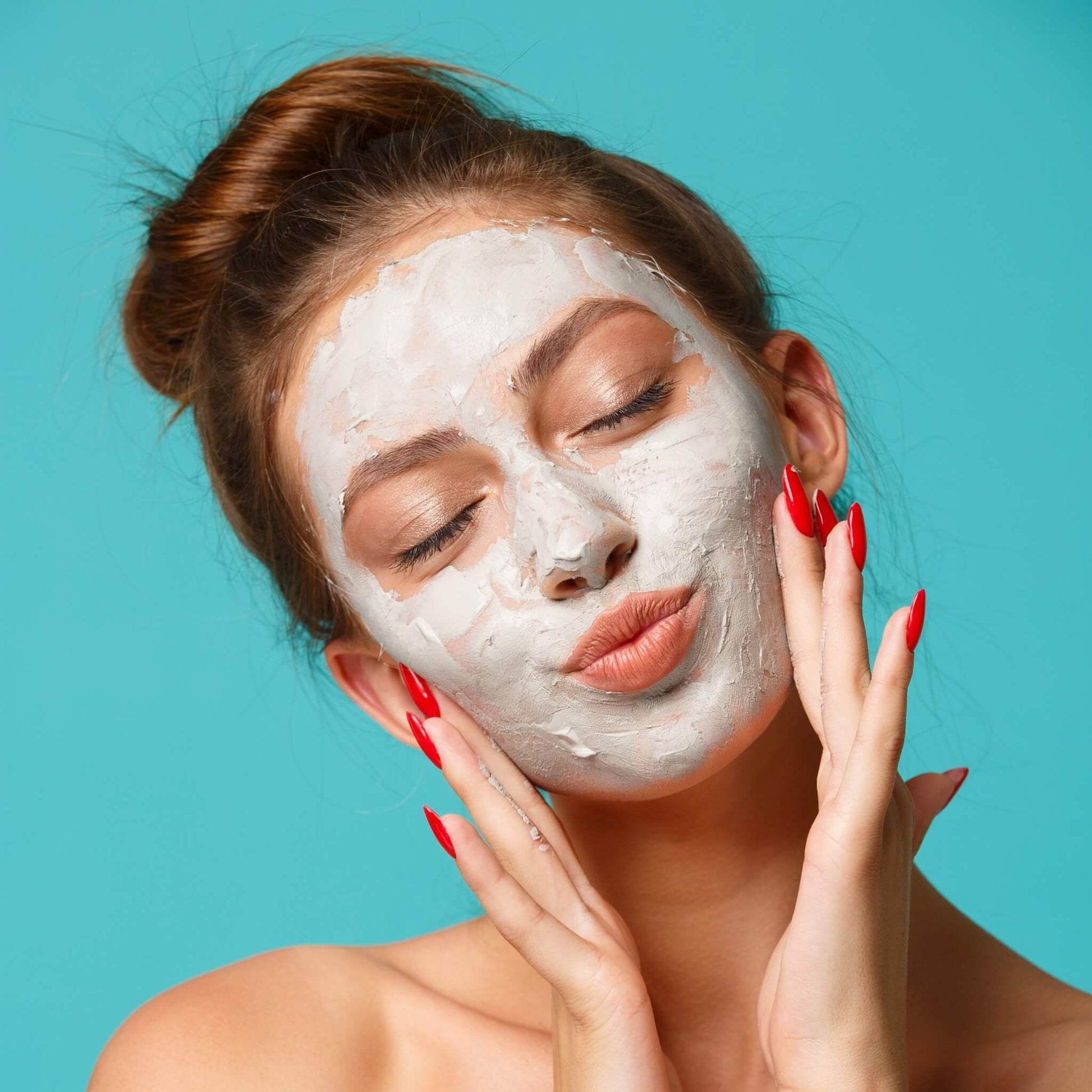 Woman with Berry Clay Face Mask applied, gently touching her face with eyes closed and glowing skin