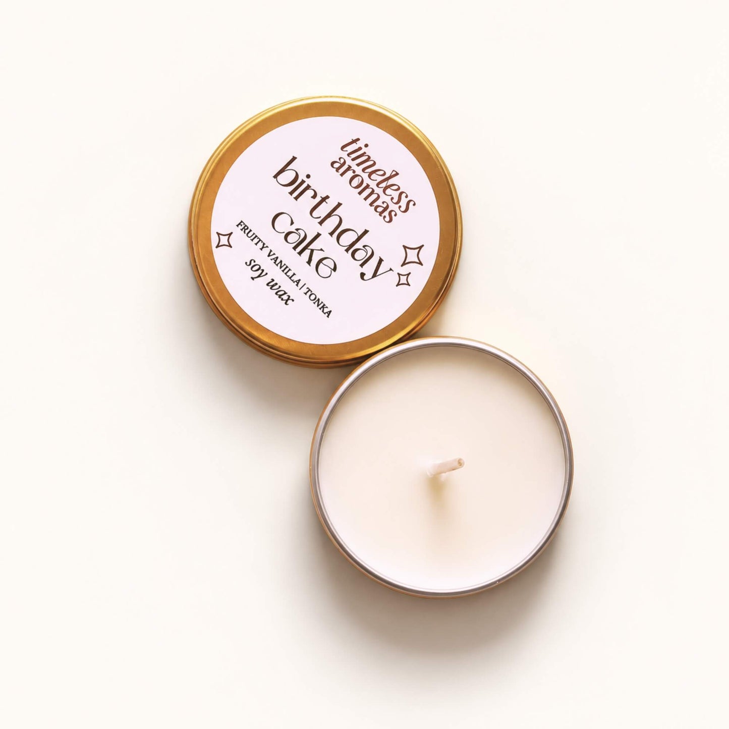 Open Birthday Cake soy wax candle in a mini gold tin with labelled lid beside it