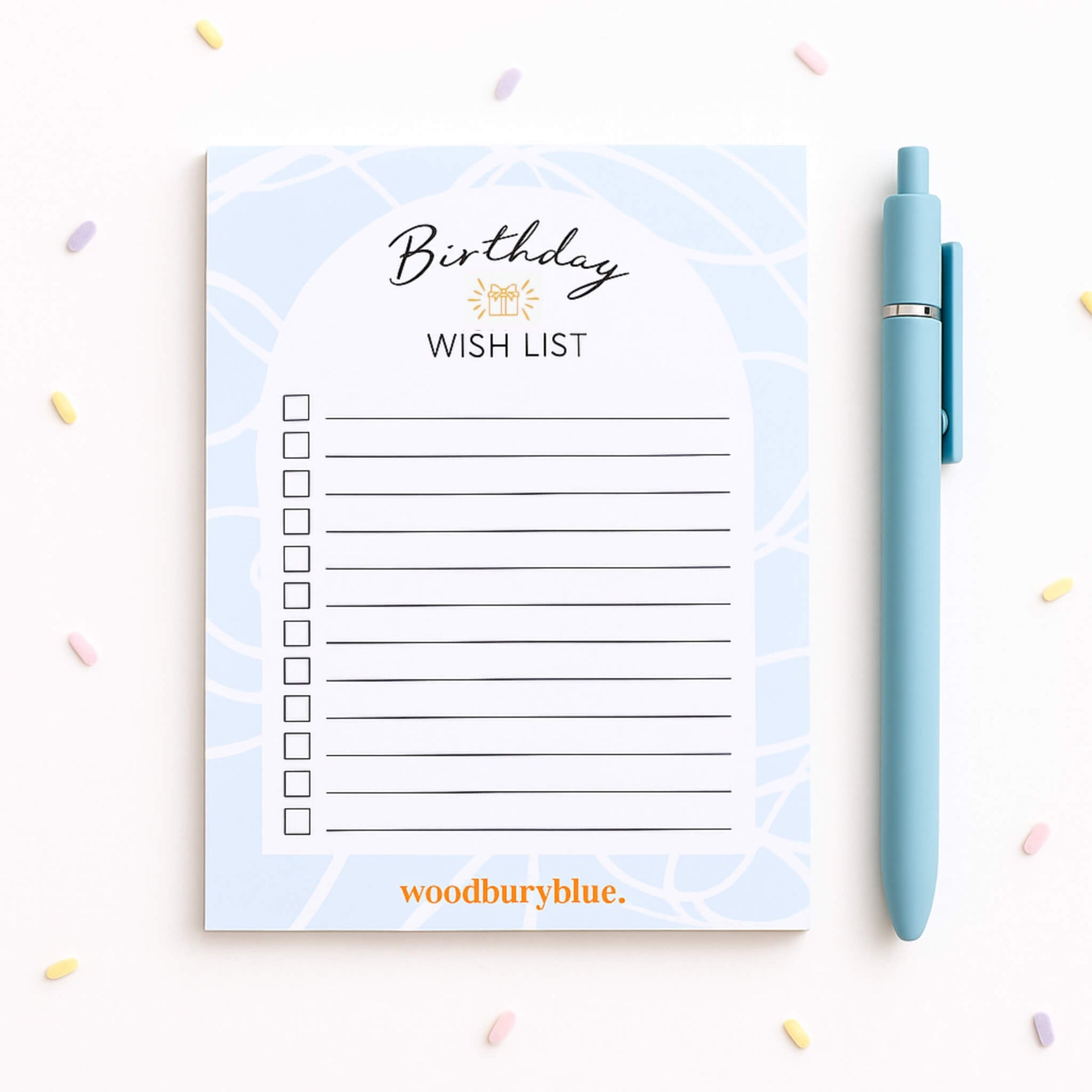 Birthday Wish List notepad in soft blue with pastel confetti background and blue pen, designed by Woodbury Blue with 50 tear-off lined pages and premium 100gsm paper.