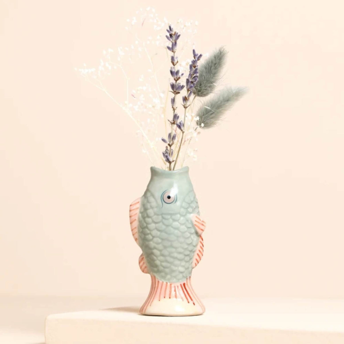Lisa Angel blue ceramic mini fish bud vase with pink fins and textured scales, displayed with dried flowers against a pale background.
