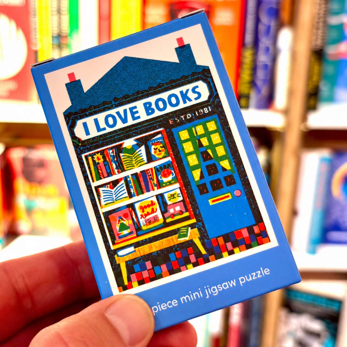 Bookshop mini jigsaw puzzle by Happily Puzzles held in front of colourful books