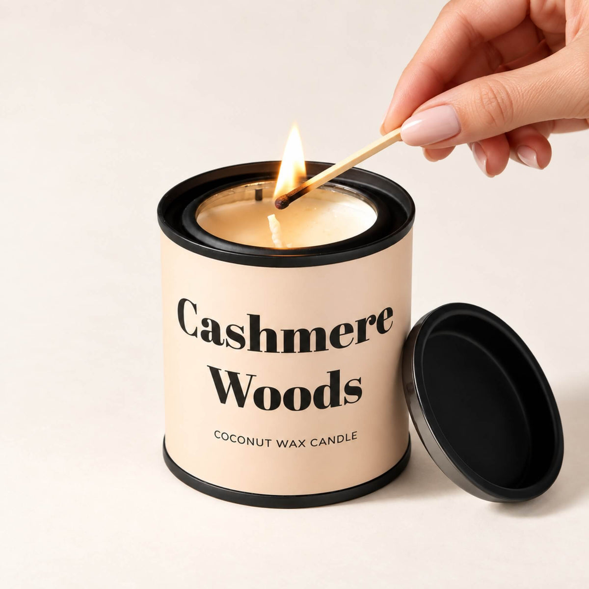 Cashmere Woods coconut wax tin candle being lit with a match