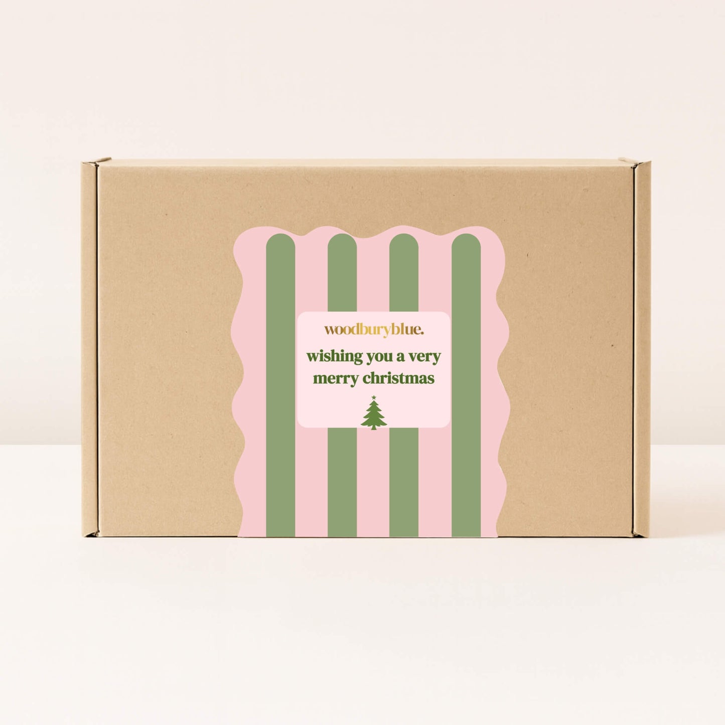 Kraft gift box with pink and green striped Christmas sticker that reads wishing you a very merry christmas from Woodbury Blue