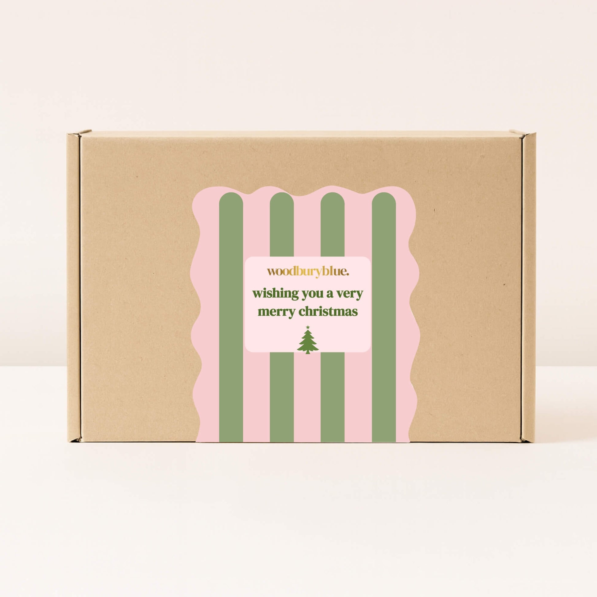Kraft gift box with pink and green striped Christmas sticker that reads wishing you a very merry christmas from Woodbury Blue