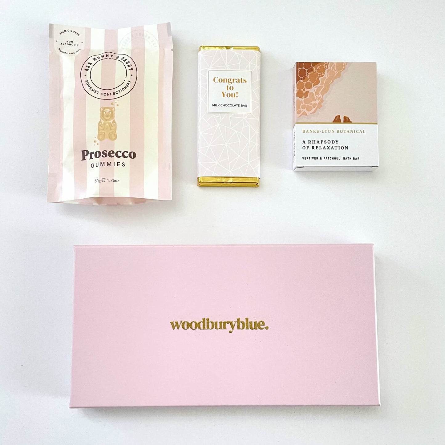 Congratulations latterbox gift set containing chocolate, sweets and a bath oil bar in a pink letterbox