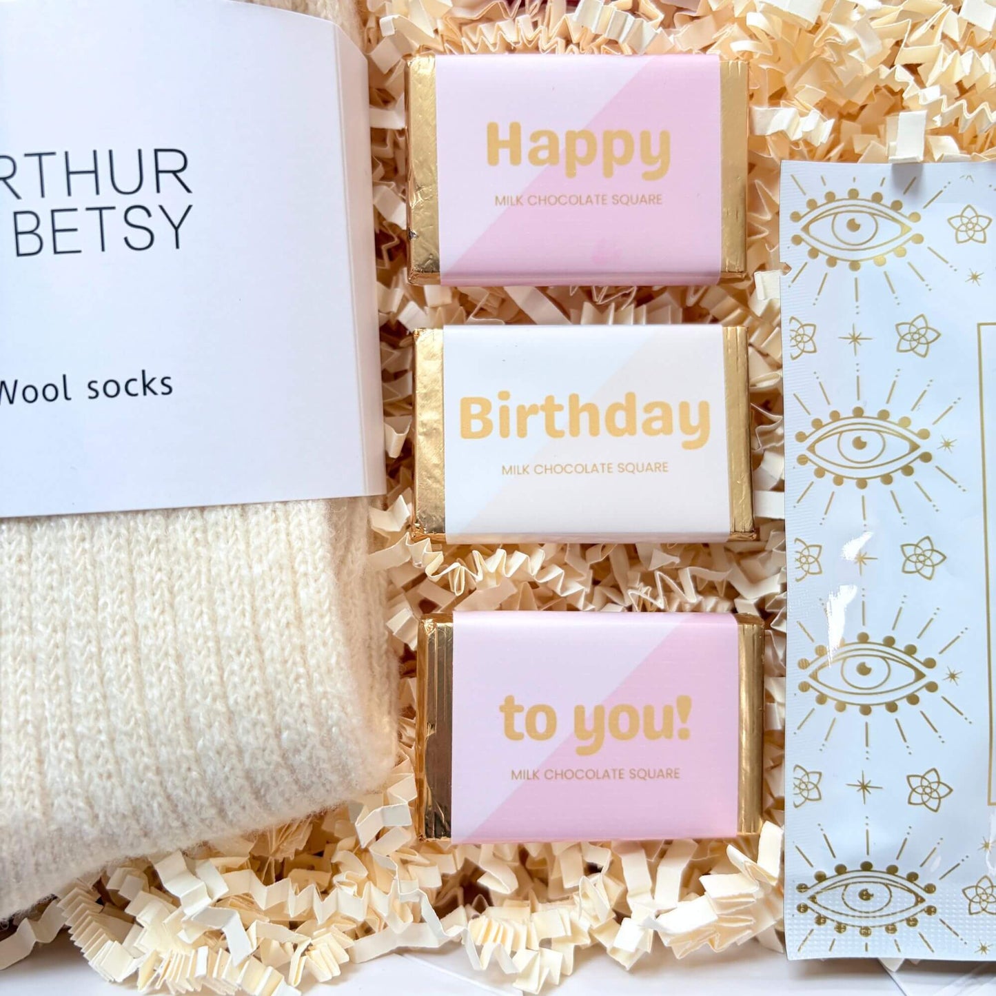 Cosy Birthday Gift Box detail showing birthday chocolate squares with wool socks and a self heating eye mask.