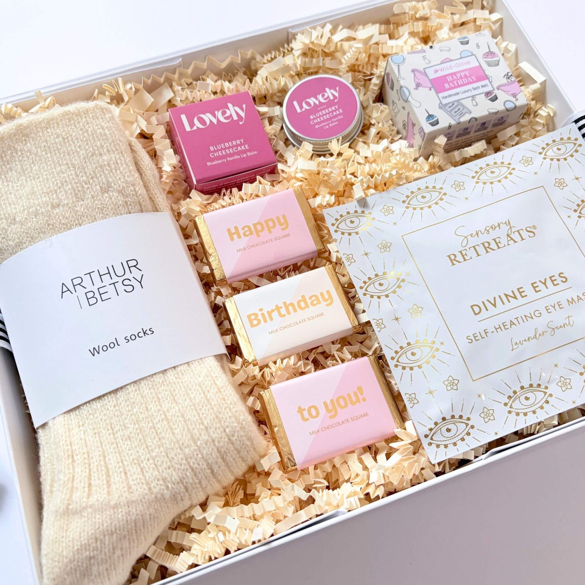 Cosy Birthday Gift Box with wool socks, self heating eye mask, blueberry cheesecake lip balm, birthday bath melt and chocolate squares.