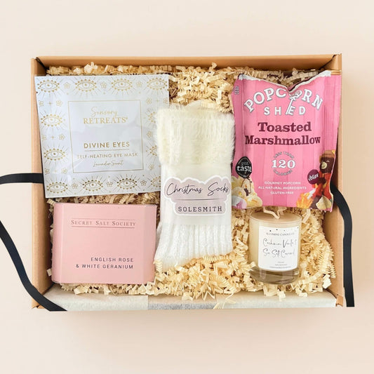 p down view of the Cosy Christmas Gift Box showing fluffy socks, Sensory Retreats eye mask, popcorn, bath soak and winter candle.