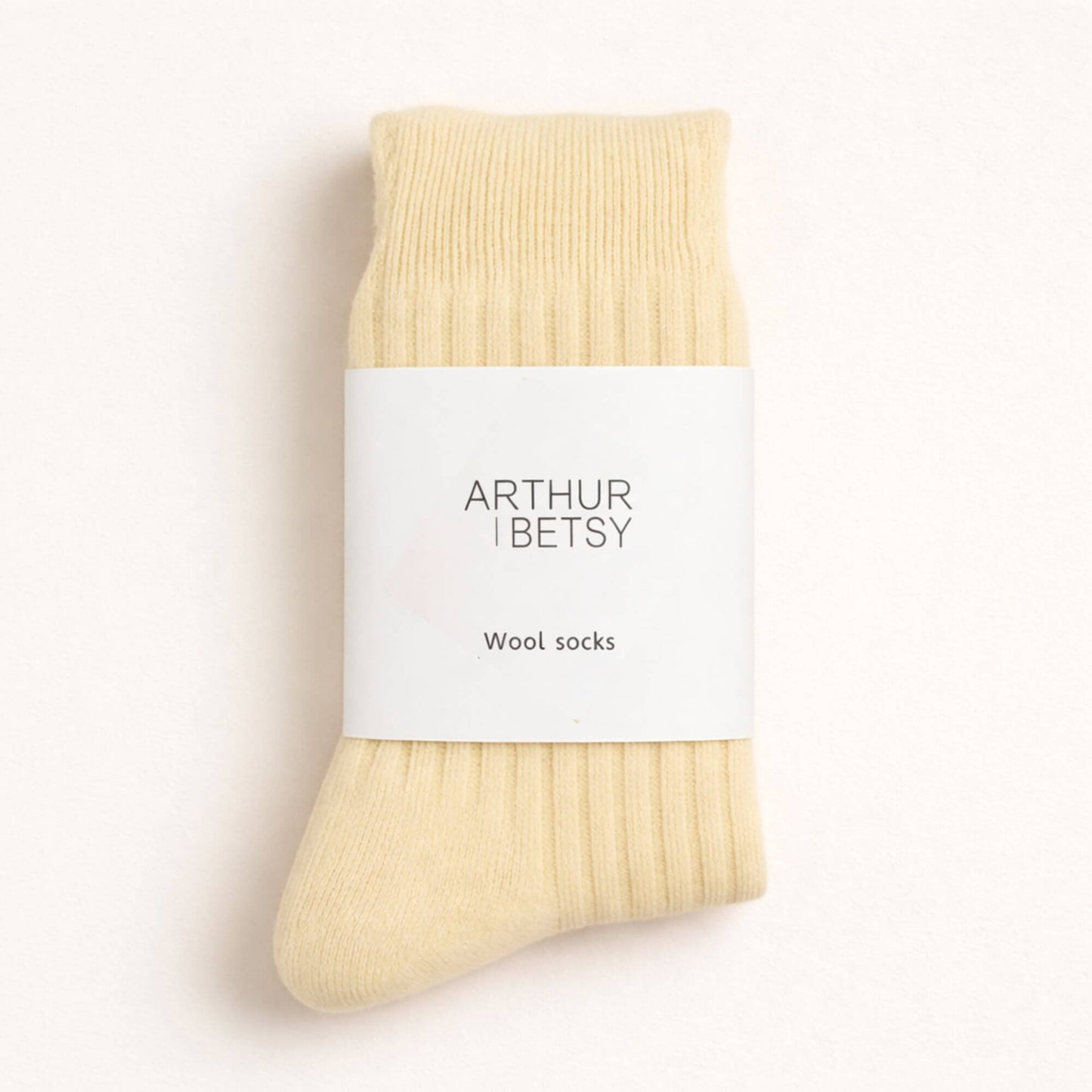 Cream wool sock by 'Arthur Betsy' on a light beige background
