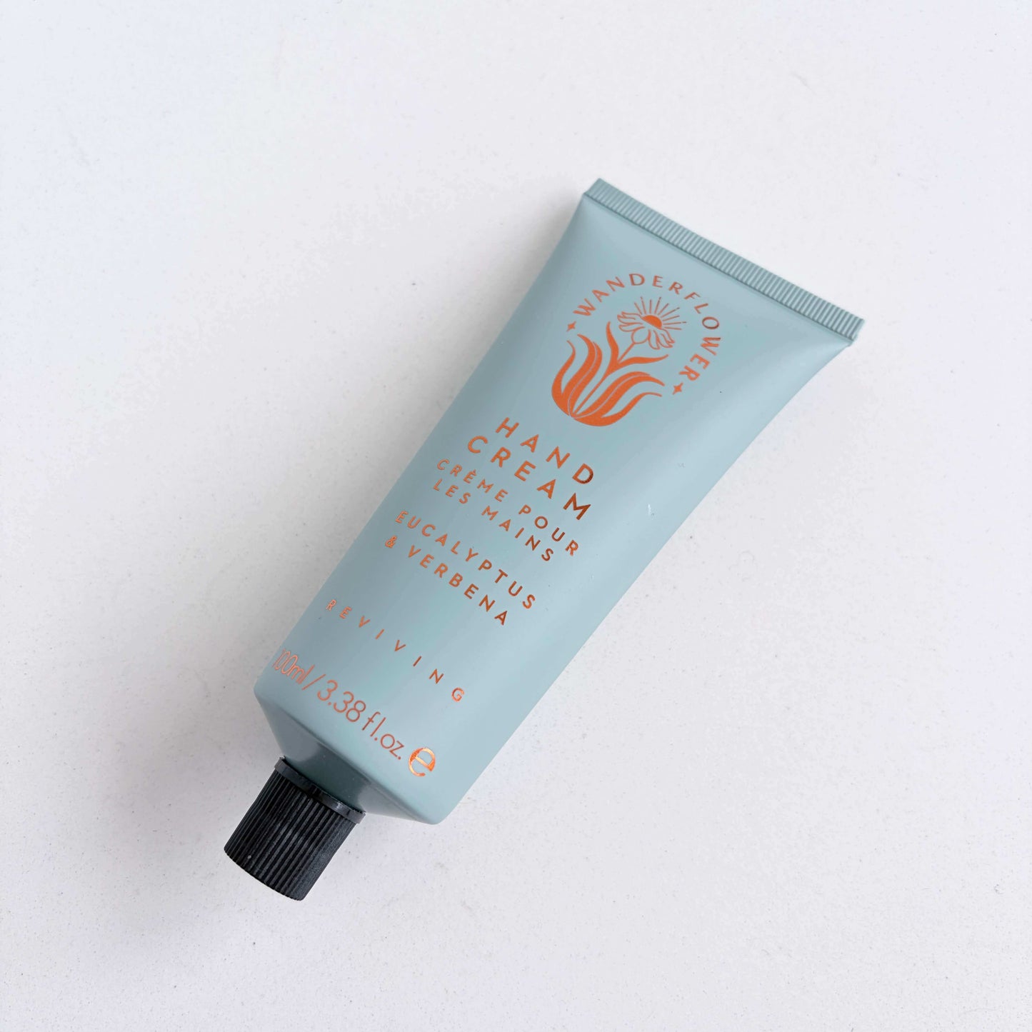 Eucalyptus and verbena hand cream tube laid flat on a light background