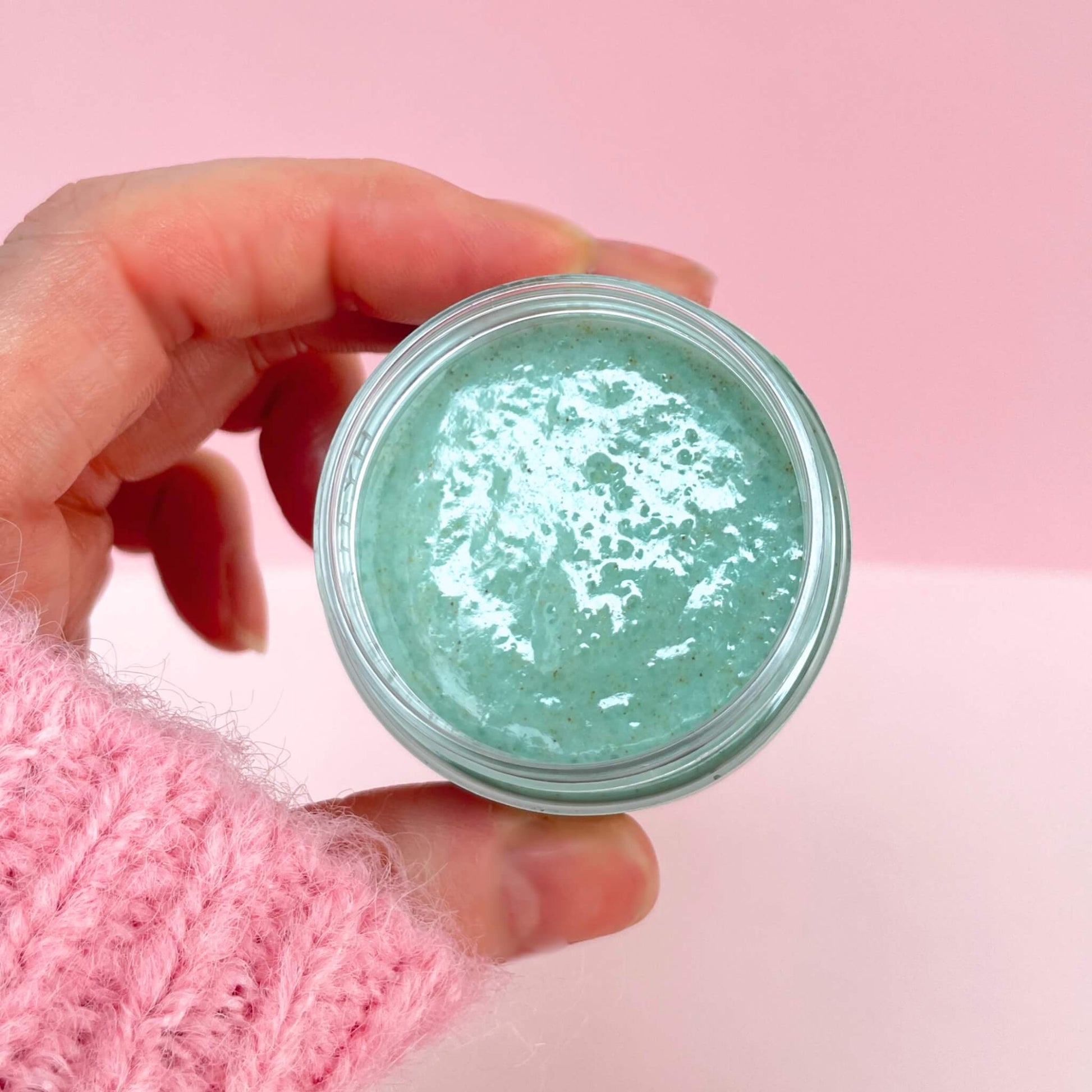 Hand showing an open pot of exfoliating mint lip scrub