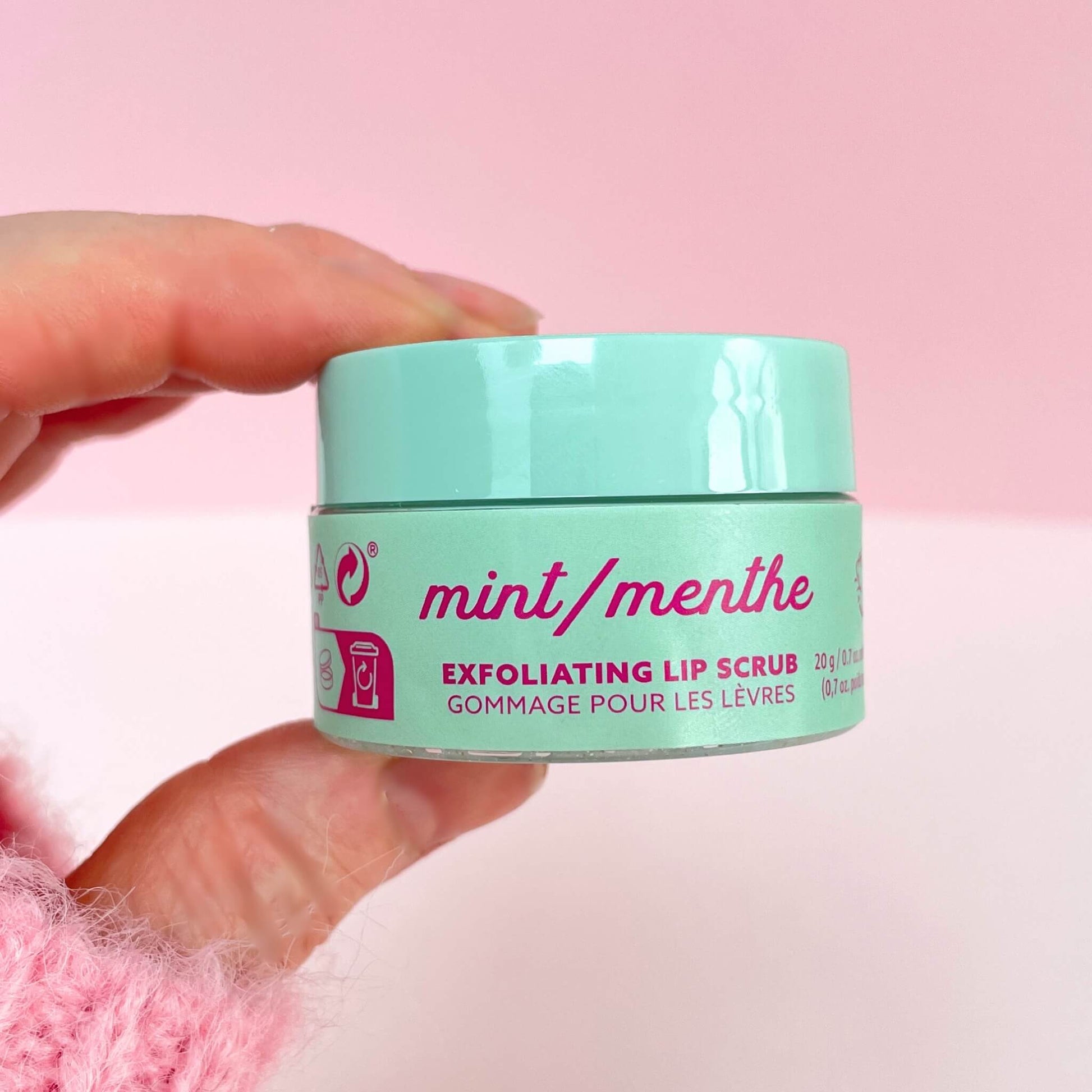 Hand holding a pot of exfoliating mint lip scrub