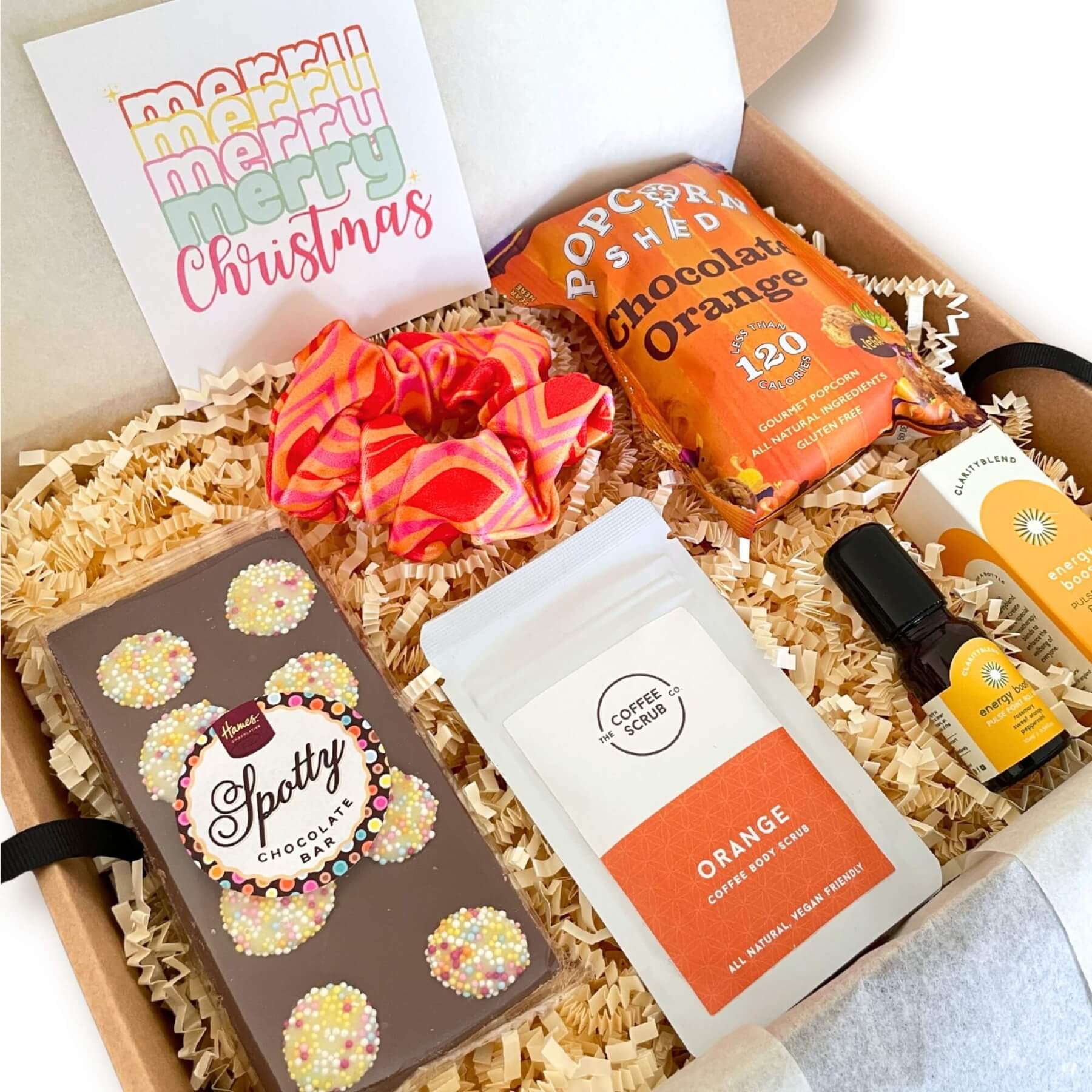 Festive Cheer Gift Box with chocolate orange popcorn, spotty chocolate bar, orange coffee scrub, energy roll on and bright scrunchie.