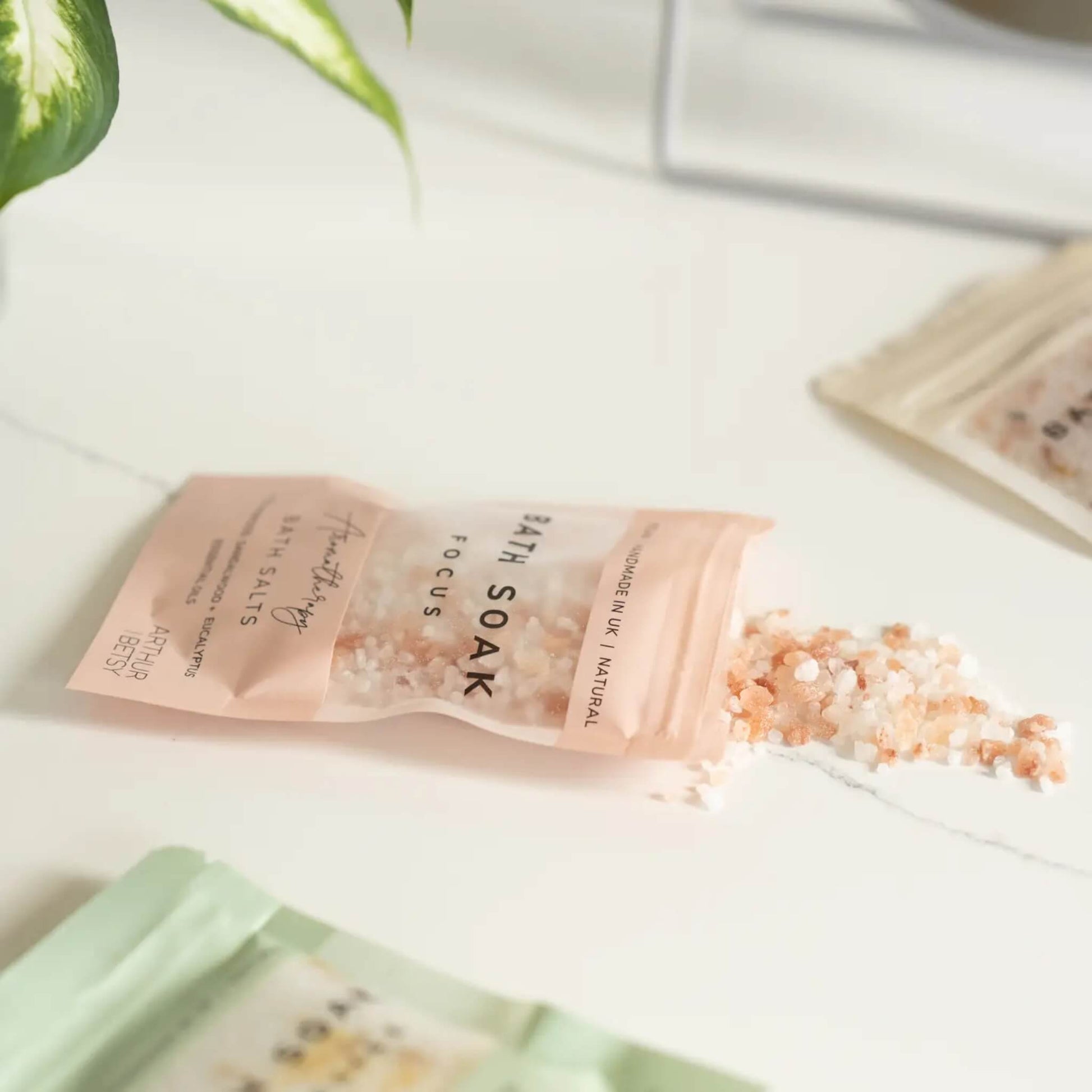 Bath salts spilling from Arthur Betsy sachet on white surface